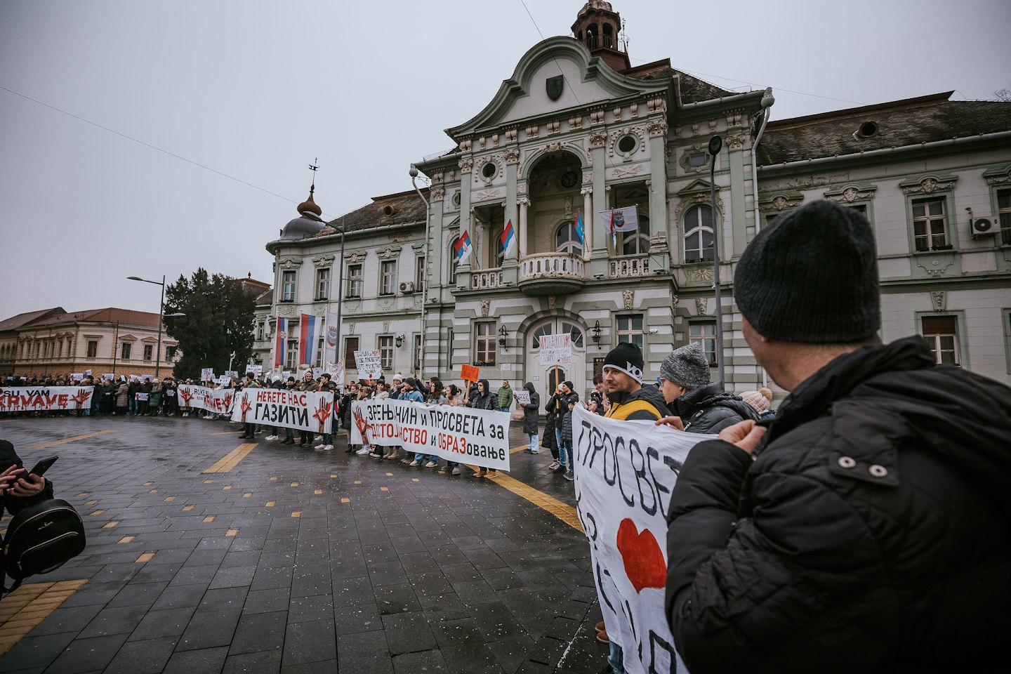 Demonstranten mit Schildern und Bannern auf einem Marktplatz.