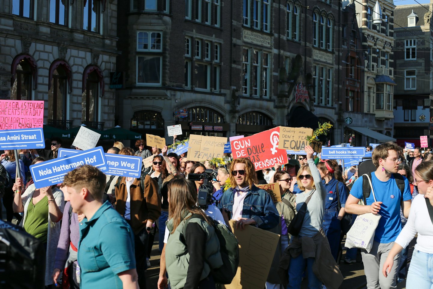 Eine Gruppe von Menschen marschiert mit Protestschildern eine Stadtstraße entlang.