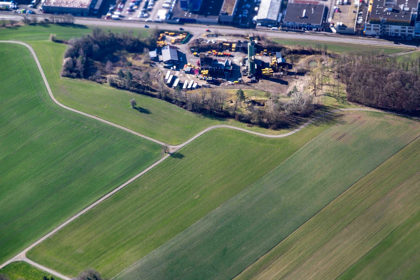 Landwirtschaftliche Felder und ein Industriekomplex bei Tageslicht.