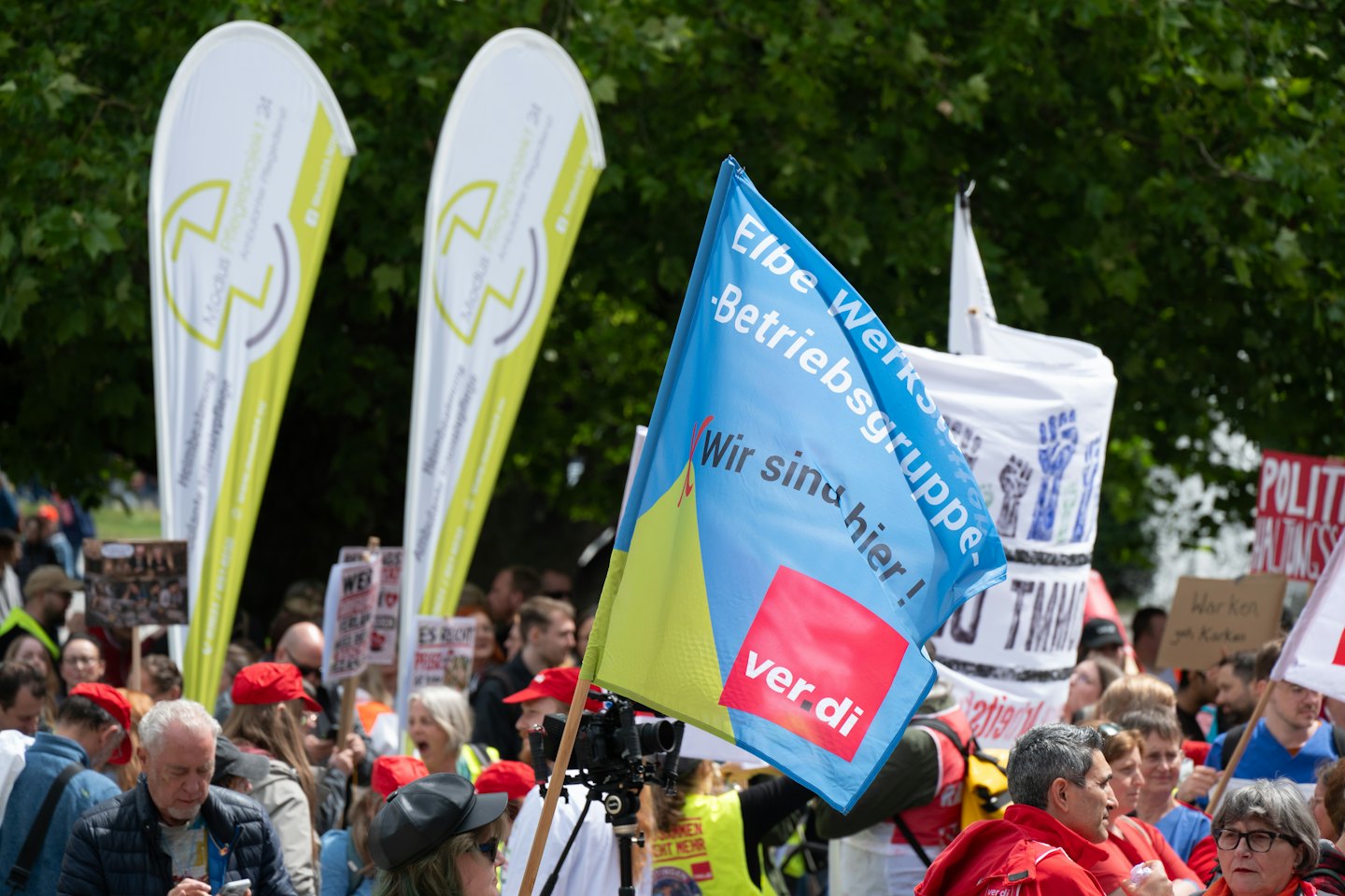 Demonstranten tragen Fahnen und Banner bei einer Kundgebung im Freien.